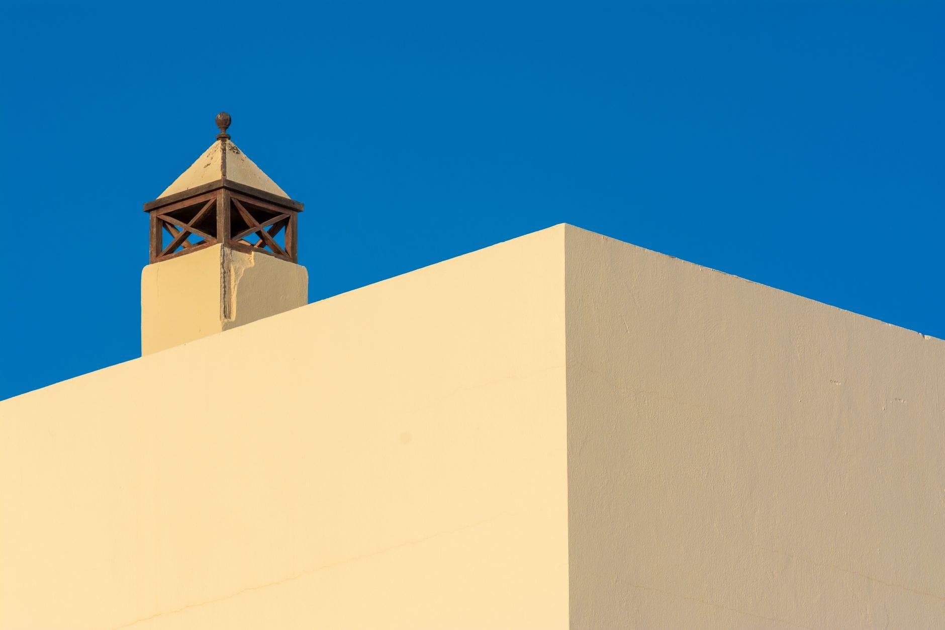 Chimney detail of minimalist architecture against a vivid blue sky.